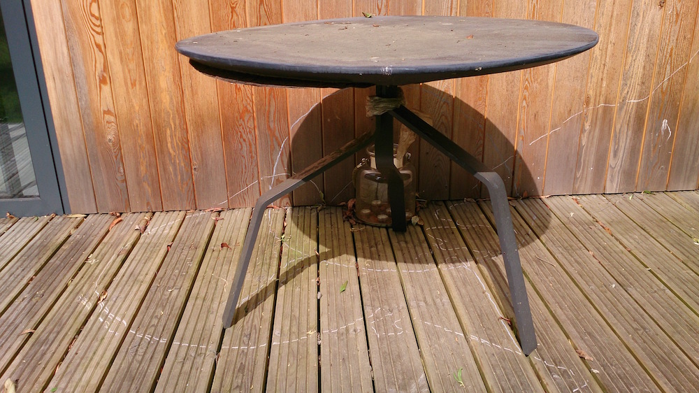 round metal table with white lines drawn on teh decking