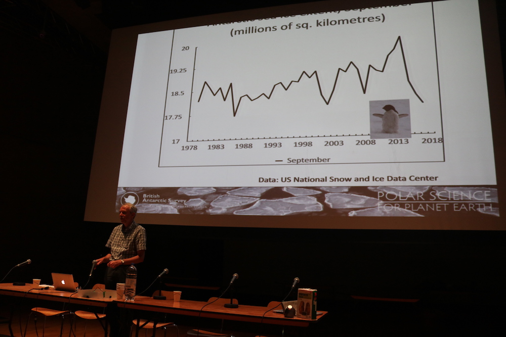 a graph of sea ice levels and John presenting at a row of tables with mircrophones